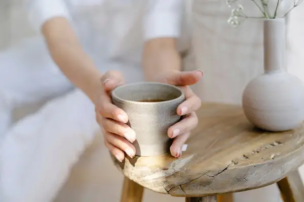 Sanfte Hände halten eine Tasse Tee. Ein Moment der Ruhe, perfekt, um abends Brennnesseltee zu trinken.