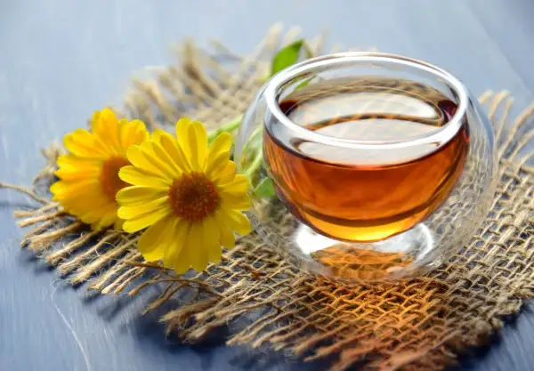 Zwei gelbe Blumen neben einer Tasse Tee. Zeit, dass das muss teewasser kochen für einen entspannenden Moment.
