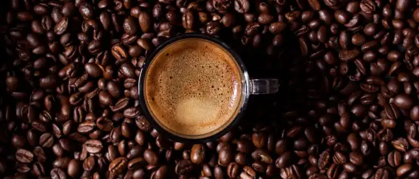 Eine Tasse Espresso auf gerösteten Kaffeebohnen. Wenn zu viel Koffein im Spiel ist, hilft Wasser und Geduld.